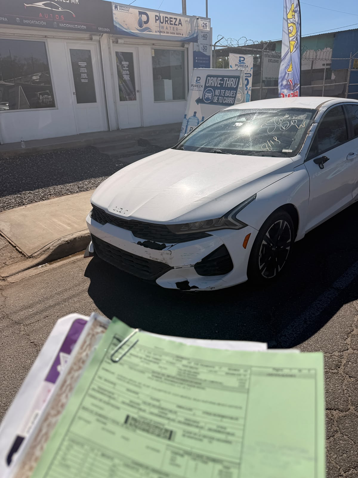 Kia blanco frente a la oficina de MR Importaciones, con documentación del trámite