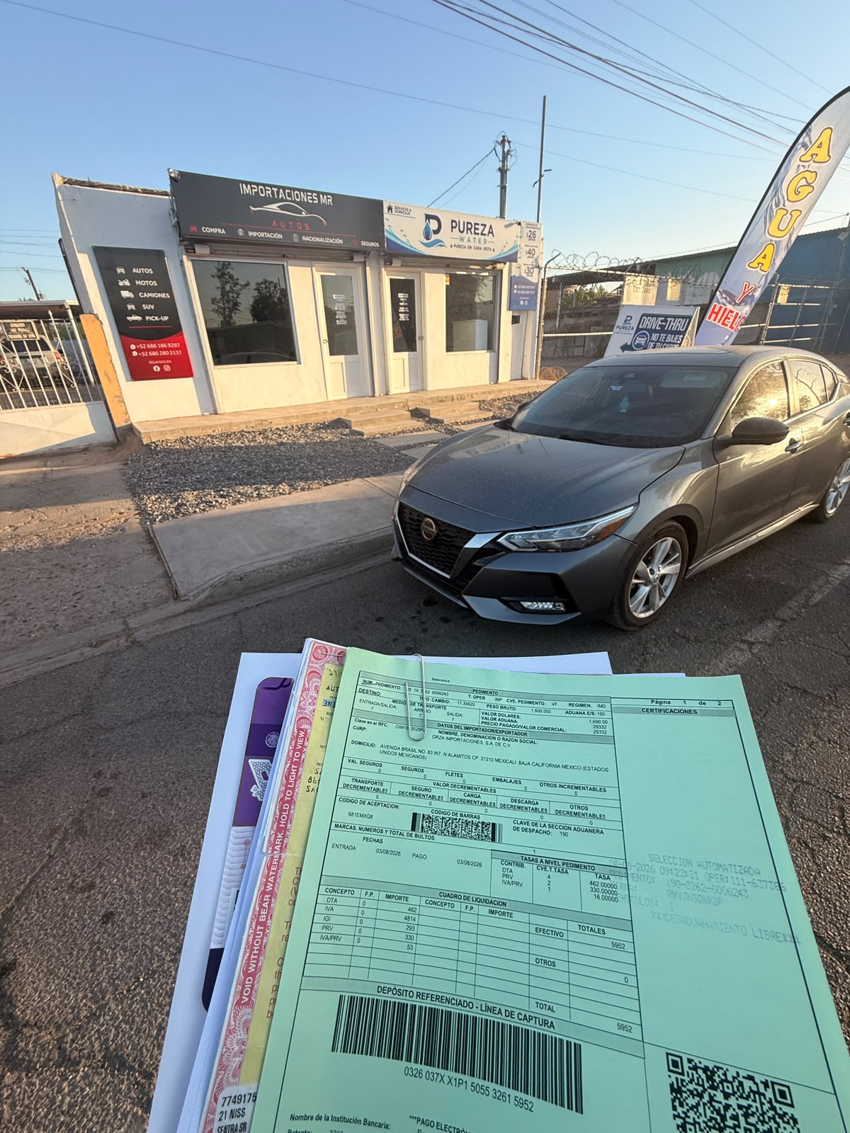 Nissan gris frente a la oficina de MR Importaciones, con documentación del trámite